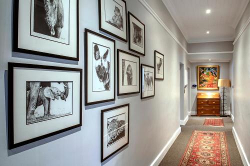 a hallway with framed pictures on a wall at La Fontaine Boutique Hotel by The Oyster Collection in Franschhoek