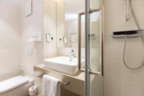 a white bathroom with a sink and a shower at Hotel Kapuzinerhof in Biberach an der Riß