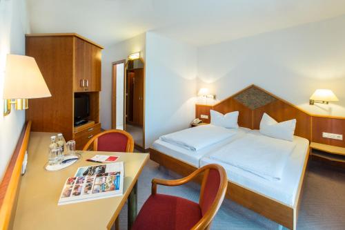 ビーベラハ・アン・デア・リスにあるホテル カプツィナホフのベッドとデスクが備わる小さなホテルルームです。
