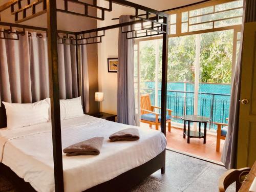 um quarto com uma cama e vista para uma varanda em Prantara Heritage Suites em Phnom Penh