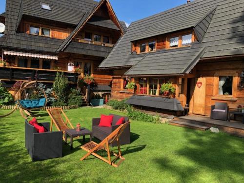 a house with a yard with chairs and tables at Apartamenty u Giewonta in Zakopane