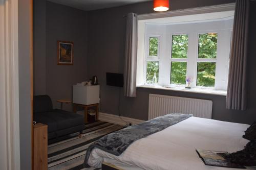1 dormitorio con cama, ventana y silla en Torwood House, en Penzance