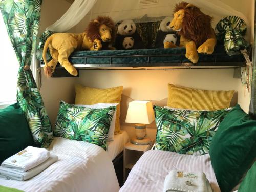 a bedroom with two beds and stuffed animals on a shelf at Villa Vravrona Tower & Suites in Markopoulo