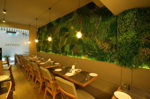 uma fila de mesas num restaurante com uma parede verde em Hotel Suncity Apollo, Colaba em Mumbai