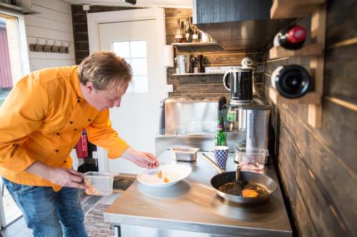 Arctic Gourmet Cabin في كيرونا: رجل واقف في مطبخ يحضر الطعام