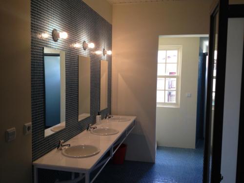 a bathroom with two sinks and two mirrors at Santiago 31 Hostel in Guimarães