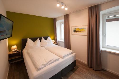 a bedroom with a white bed with a green wall at Appartements Marlene in Maishofen