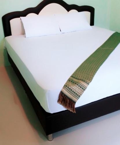 a white bed with a black bed frame and a blanket at Raina-Suanpa Lung Sood Farmstay in Ban Mot Deng
