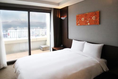 a bedroom with a large white bed and a large window at Mstay Hotel in Seogwipo