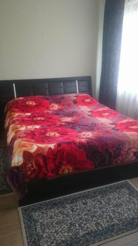 1 cama con manta roja y 2 alfombras en el suelo en Vila Nature - Rosia Montana en Abrud