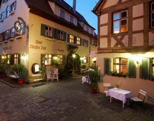 cortile con tavoli e sedie di fronte agli edifici di Hotel Weisses Ross a Dinkelsbühl