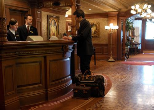 a man standing at a bar with a suitcase at Prince of Wales in Niagara on the Lake