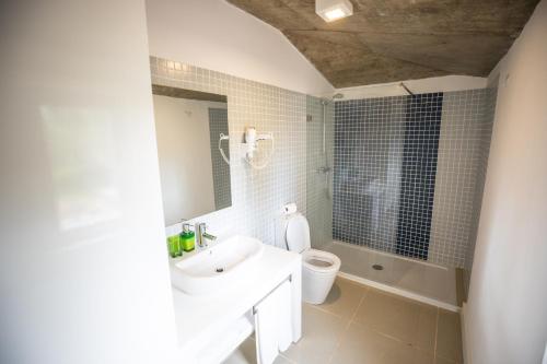 a white bathroom with a sink and a toilet at Roça Santo António Ecolodge in São Tomé