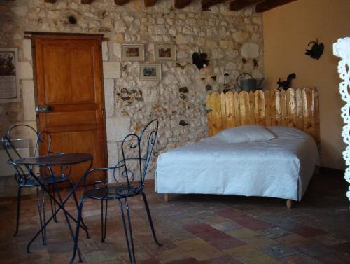 a bedroom with a bed and two chairs and a door at Coté Jardin in Villiers-sur-Loir