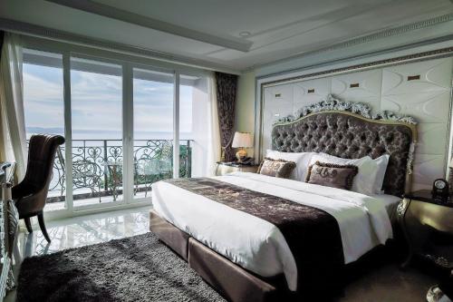 a bedroom with a large bed and a large window at LK Emerald Beach - SHA Extra Plus in Pattaya North