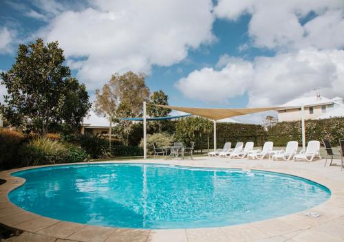 a large swimming pool with chairs and a canopy at Geographe Cove Resort in Dunsborough