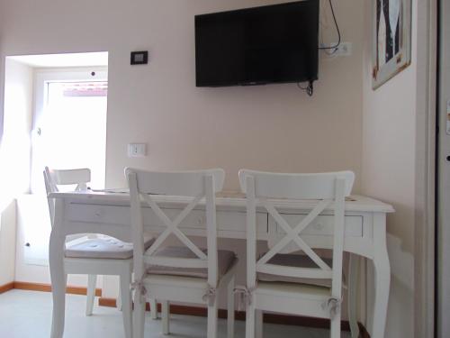 a white dining room table with two chairs and a flat screen tv at La Casetta in Tellaro