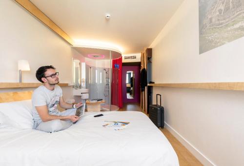 een man op een bed in een hotelkamer bij Nomad Hotel le Havre in Le Havre