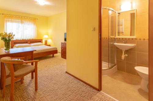 a bathroom with a shower and a sink and a bed at Pensjonat Marynarski - Apartamenty in Darłówko