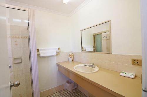 a bathroom with a sink, toilet and mirror at Aquarius Merimbula in Merimbula