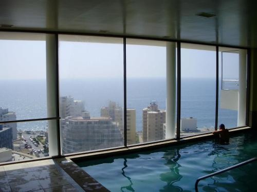 una mujer sentada en una piscina en un rascacielos en Departamento Viña del Mar, en Viña del Mar