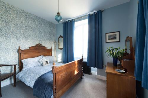 a bedroom with a bed with blue walls and a window at Evelix, The Old School House in Muir of Ord