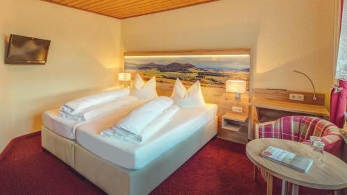 ein Schlafzimmer mit einem großen weißen Bett und einem Tisch in der Unterkunft Landhotel Zur Grünen Kutte in Bernshausen