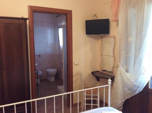 a bathroom with a toilet and a television on the wall at Bed and Breakfast Val Di Lupa in Castellina Marittima