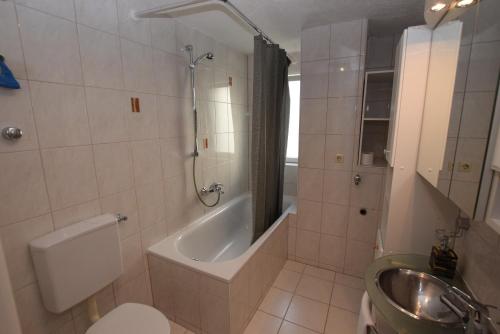 a bathroom with a tub and a toilet and a sink at AB Apartment Objekt 114 in Fellbach