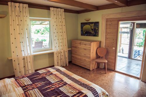 a bedroom with a bed and a dresser and windows at Pamario Krašto Sodyba in Grumbliai