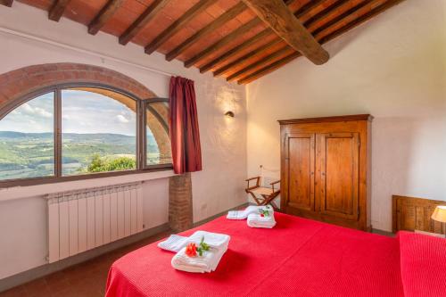 Schlafzimmer mit einem roten Bett und einem großen Fenster in der Unterkunft Fattoria Querceto in Tavarnelle in Val di Pesa