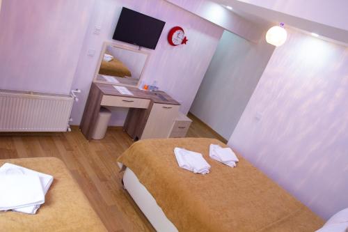 a room with two beds and a desk and a mirror at Figen Hotel in Çanakkale