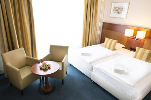 a hotel room with two beds and a table and chairs at Hotel Marttel in Karlovy Vary