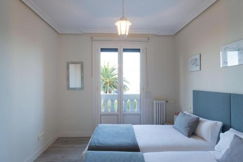 a white bedroom with a bed and a window at Atlantic - Iberorent Apartments in San Sebastián