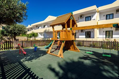 a playground with a wooden play structure in front of a building at Pefkos Village Resort in Pefki