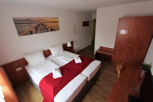 a bedroom with a bed with a red blanket on it at Hotel Leo Mühlhausen in Mühlhausen