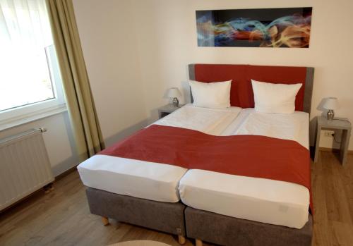 a bedroom with a large bed with a red headboard at Hotel Leo Mühlhausen in Mühlhausen