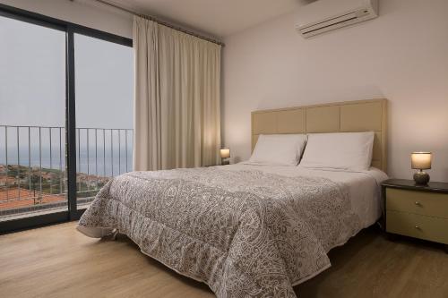 a bedroom with a bed and a large window at OurMadeira - Casa da Rosalina, superb in Calheta