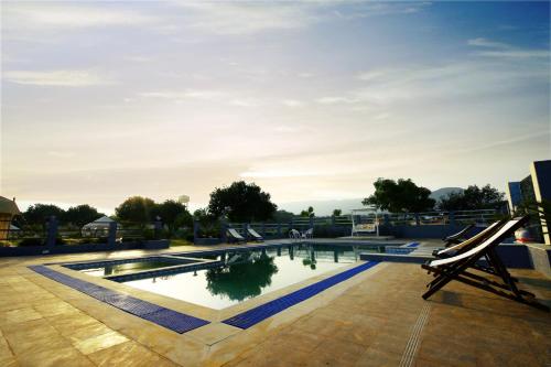 a swimming pool with two lounge chairs in front of it at Rawai Luxury Tents Pushkar in Pushkar