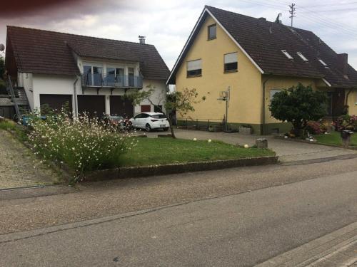 a yellow house and a white car on a street at Breig,s Ferienwohnung in Broggingen