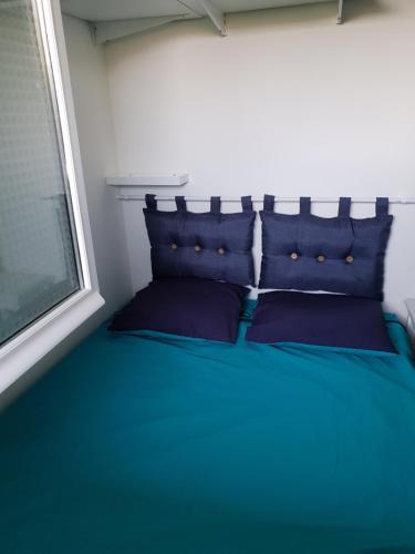 een bed met blauwe kussens in een kamer met een raam bij Appartement vue sur golf in Talmont