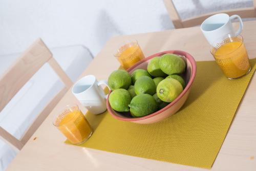 a bowl of limes on a table with glasses of orange juice at Anna Maria in Malia