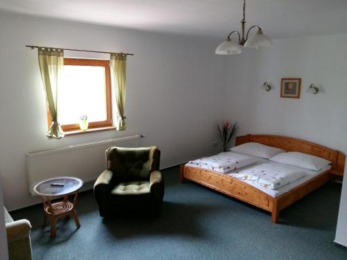 a bedroom with a bed and a chair and a window at Pension U Stříbrného Jelena in Cheb