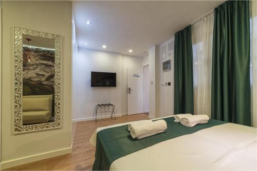 a bedroom with a bed with a mirror and green curtains at Hotel Ciudad del Mar in Las Palmas de Gran Canaria