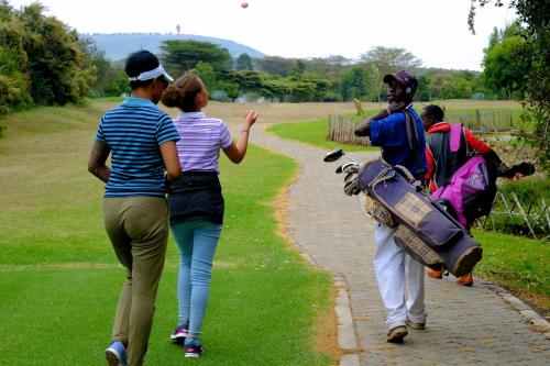 a group of people walking down a dirt road at The Great Rift Valley Lodge & Golf Resort in Naivasha