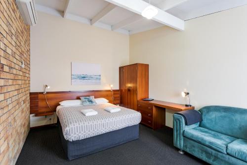 um quarto com uma cama e um sofá azul em Albany Holiday Units em Albany