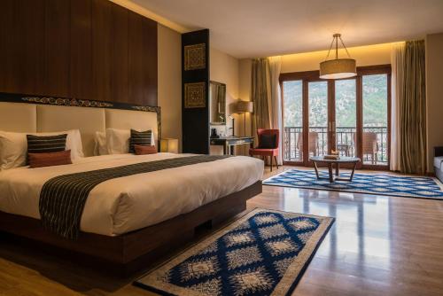 a bedroom with a bed and a table and a balcony at Norkhil Boutique Hotel & Spa in Thimphu