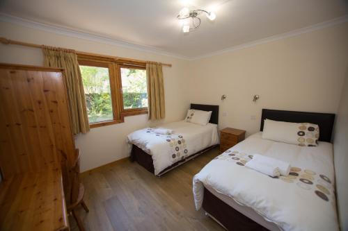 a bedroom with two beds and a window at Invercauld Lodges in Ballater