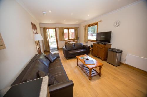 a living room with a leather couch and a television at Invercauld Lodges in Ballater