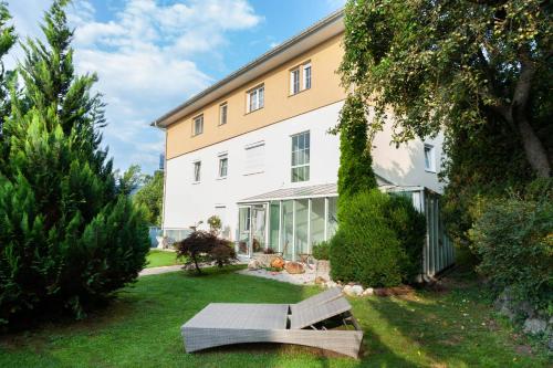 a bench sitting in the grass in front of a building at Hotel Plattenwirt in Klagenfurt